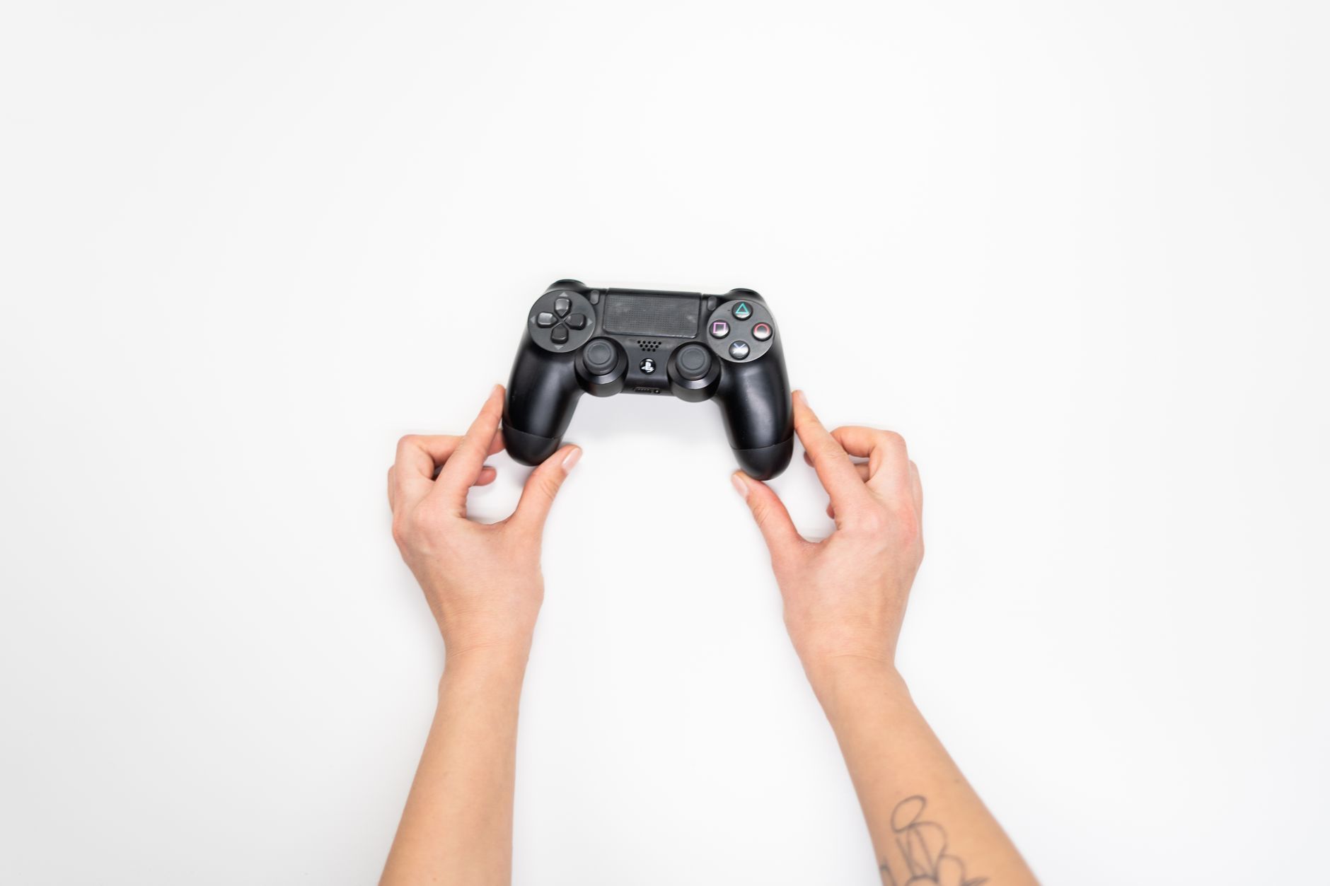 Vue de dessus de mains tenant une manette de jeu noire sur fond blanc.