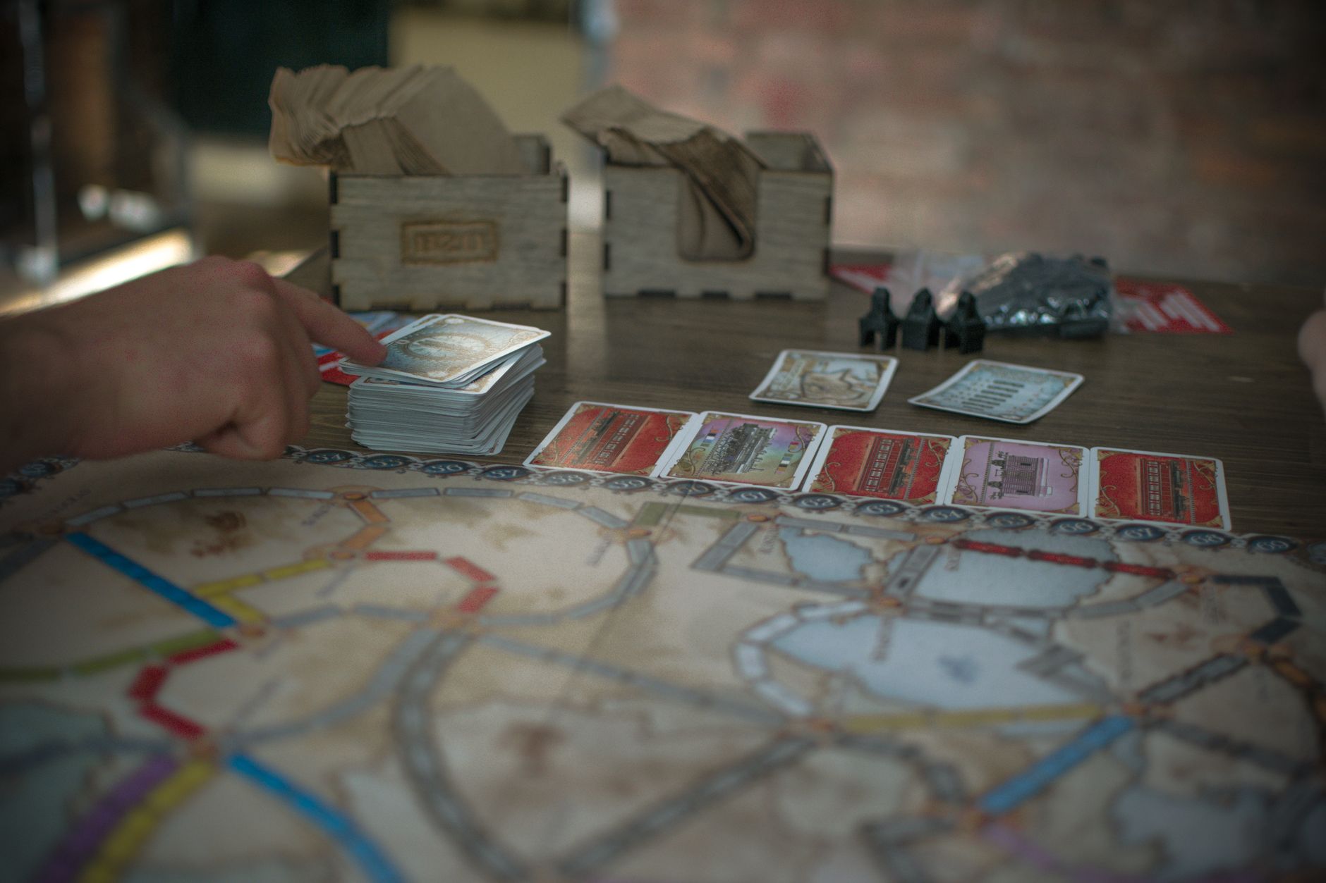 Gros plan d'une session de jeu de société stratégique avec des cartes et des mains, mettant en évidence les composants du jeu et le jeu.