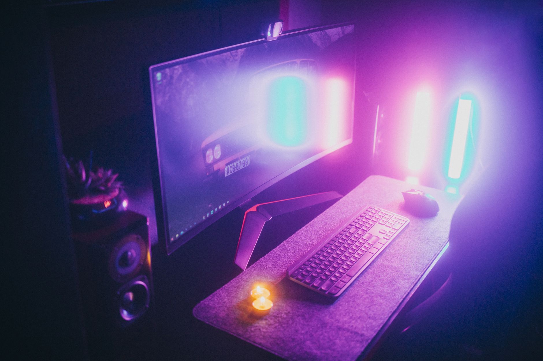 Un bureau de jeu élégant avec des lumières néon, un clavier et un moniteur dans une pièce sombre.