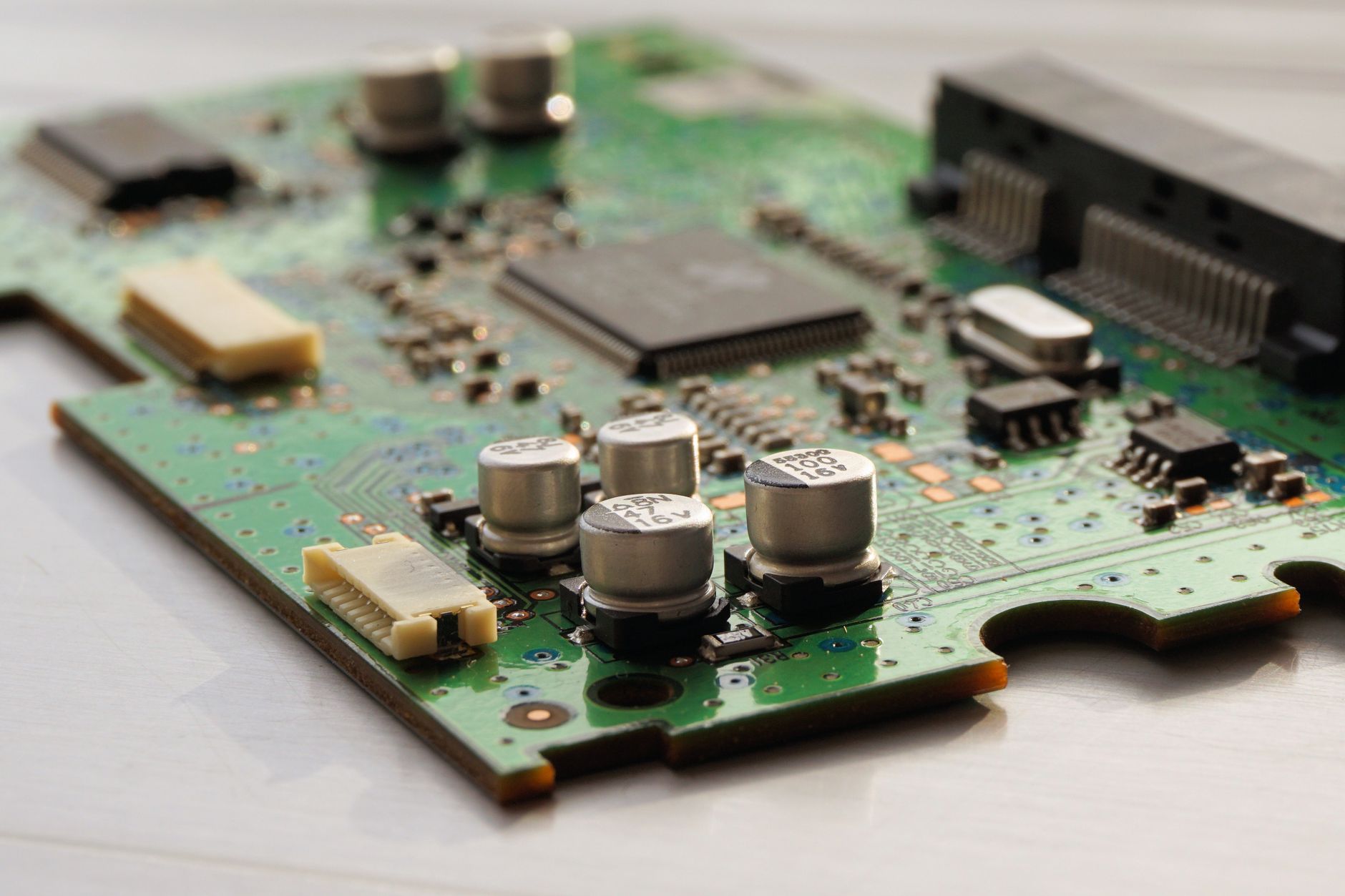 Circuit imprimé vert vu en gros plan, avec condensateurs, puces et connecteurs